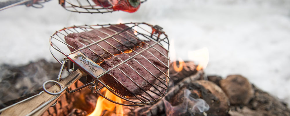 Über dem Feuer geräuchertes Rentier mit Süßkartoffeln